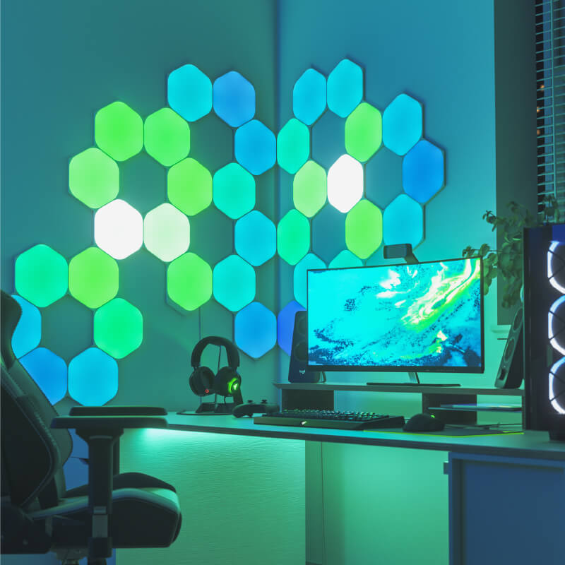 Nanoleaf Shapes Thread-enabled color-changing hexagon smart modular light panels mounted to a wall above a battlestation. Similar to Philips Hue, Lifx. HomeKit, Google Assistant, Amazon Alexa, IFTTT.