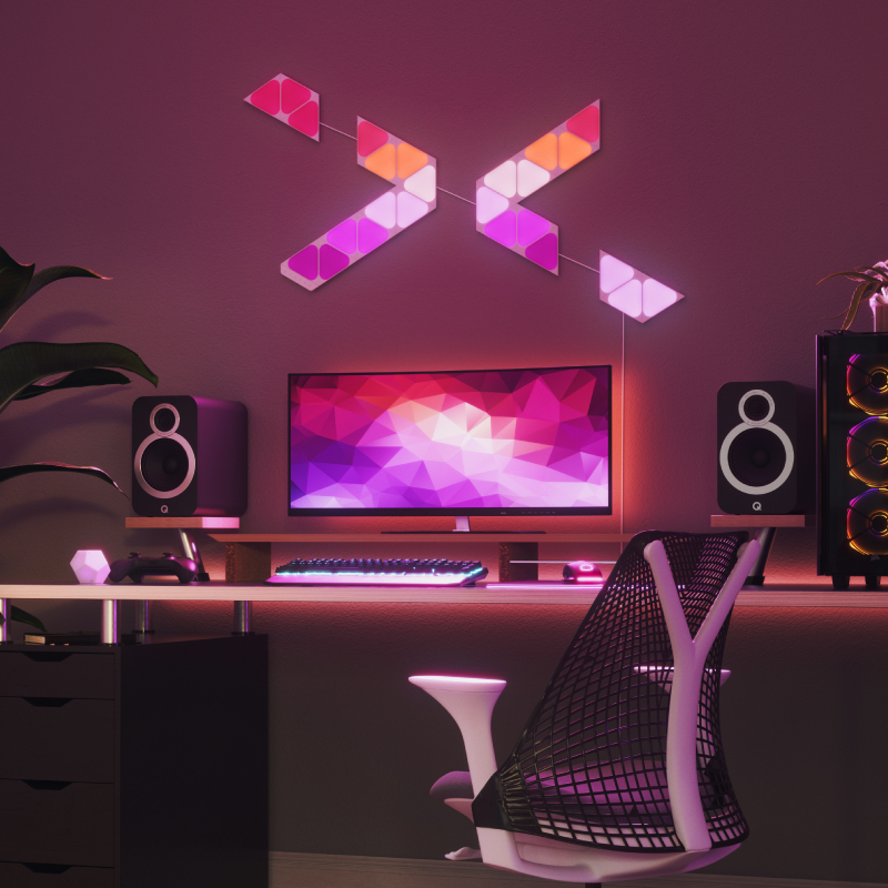 Nanoleaf Shapes Thread-enabled color-changing mini triangle smart modular light panels mounted to a wall above a battlestation. Similar to Philips Hue, Lifx. HomeKit, Google Assistant, Amazon Alexa, IFTTT.